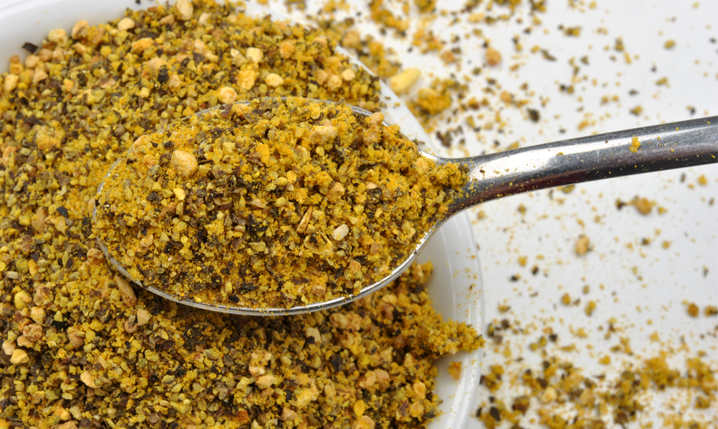 a bowl of lemon pepper with a spoonful of lemon pepper in the foreground