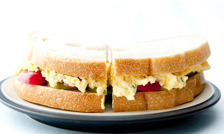a plate holding an egg salad sandwich