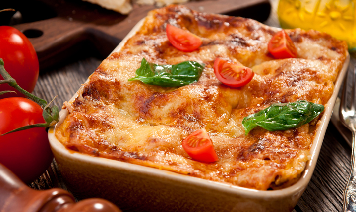an oven dish containing baked lasagna topped with fresh diced tomatoes