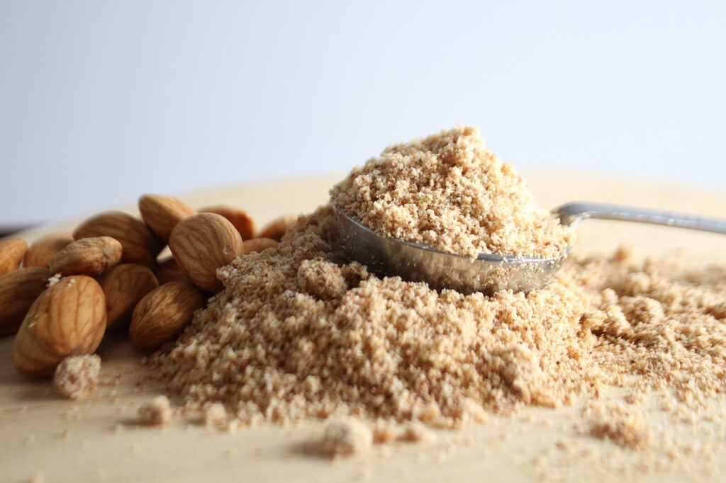 Almond flour in a spoon next to whole almonds