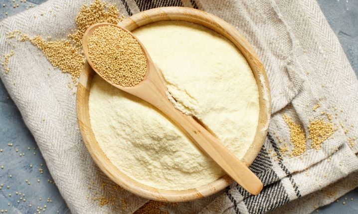 ground amaranth flour in a bowl with a wooden spoon on top containing amaranth seeds
