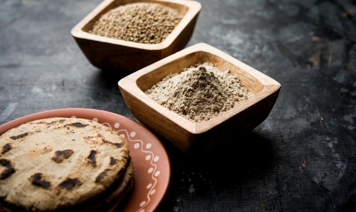 Sorghum flour and grains in two bowls next to some sorghum bread