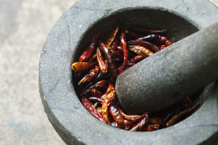 a pestle and mortar with dried cayenne peppers